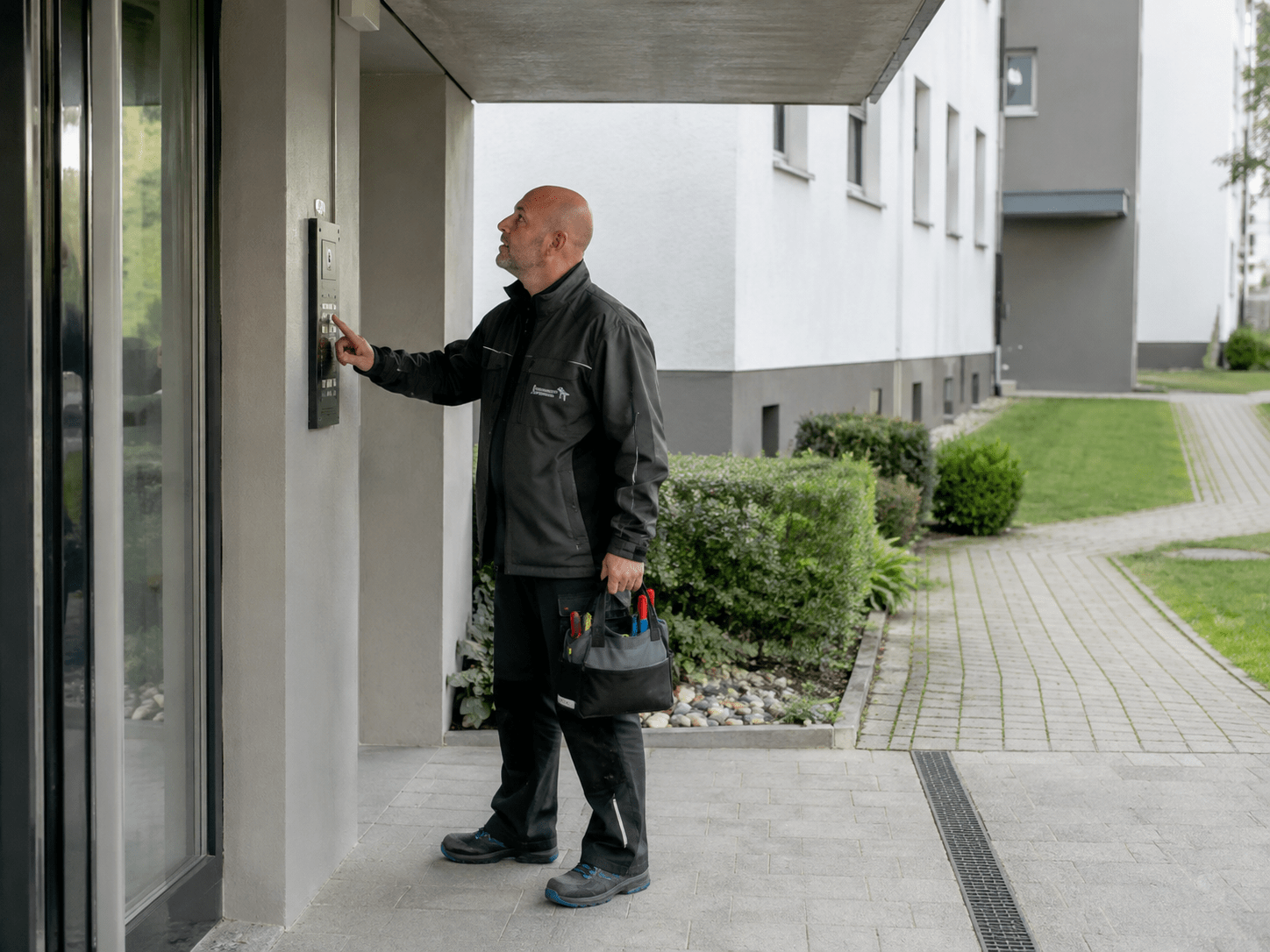 Hausmeister Krause kontrolliert den Eingangsbereich, die Klingelanlage und sichtbare Gebäudeteile einer Wohnanlage